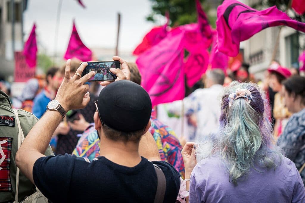 Myself in a purple t-shirt with pink XR flags in the background, next to a member of the public in a black t-shirt